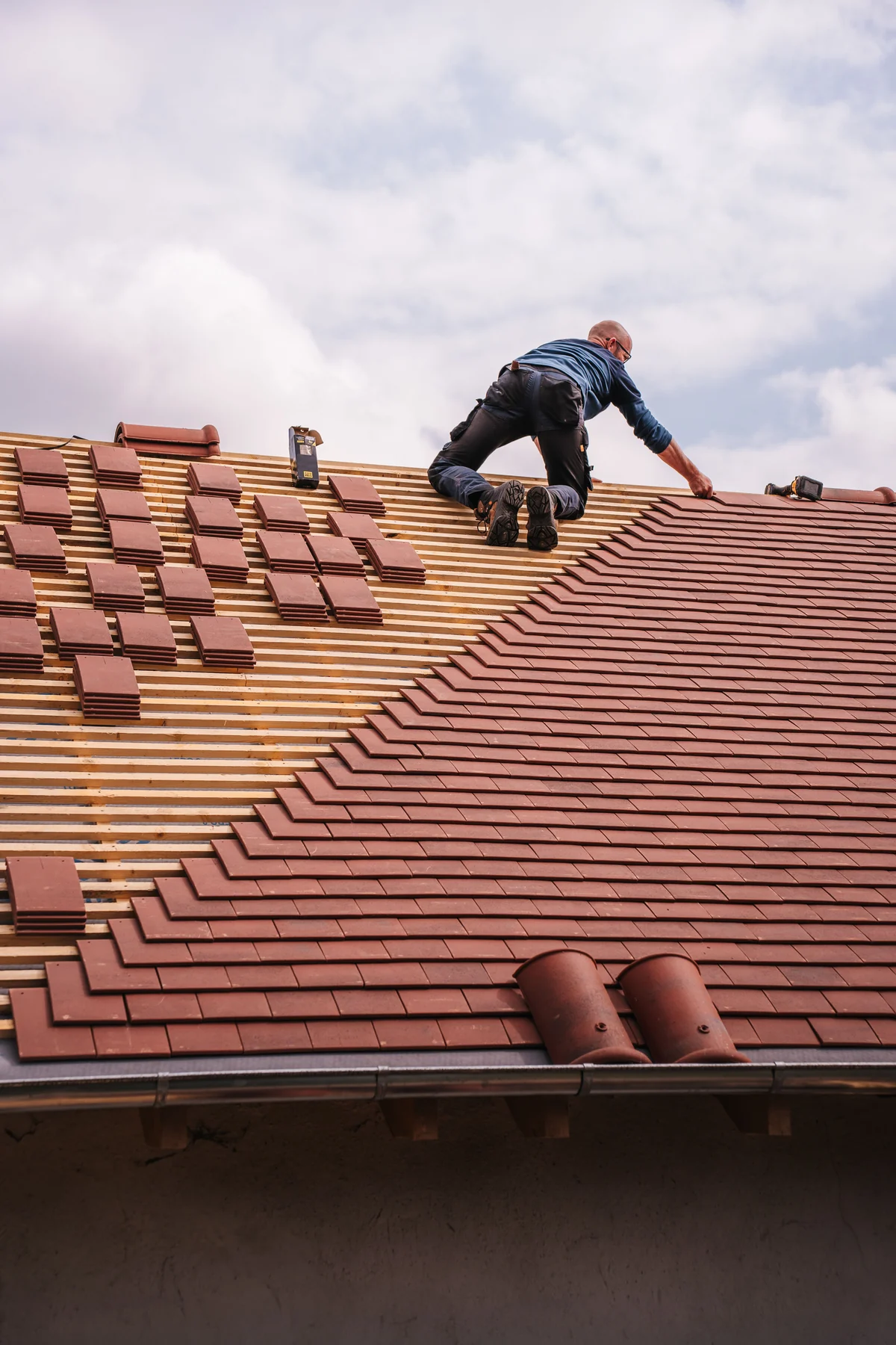 Couvreur installant des tuiles sur une toiture en rénovation